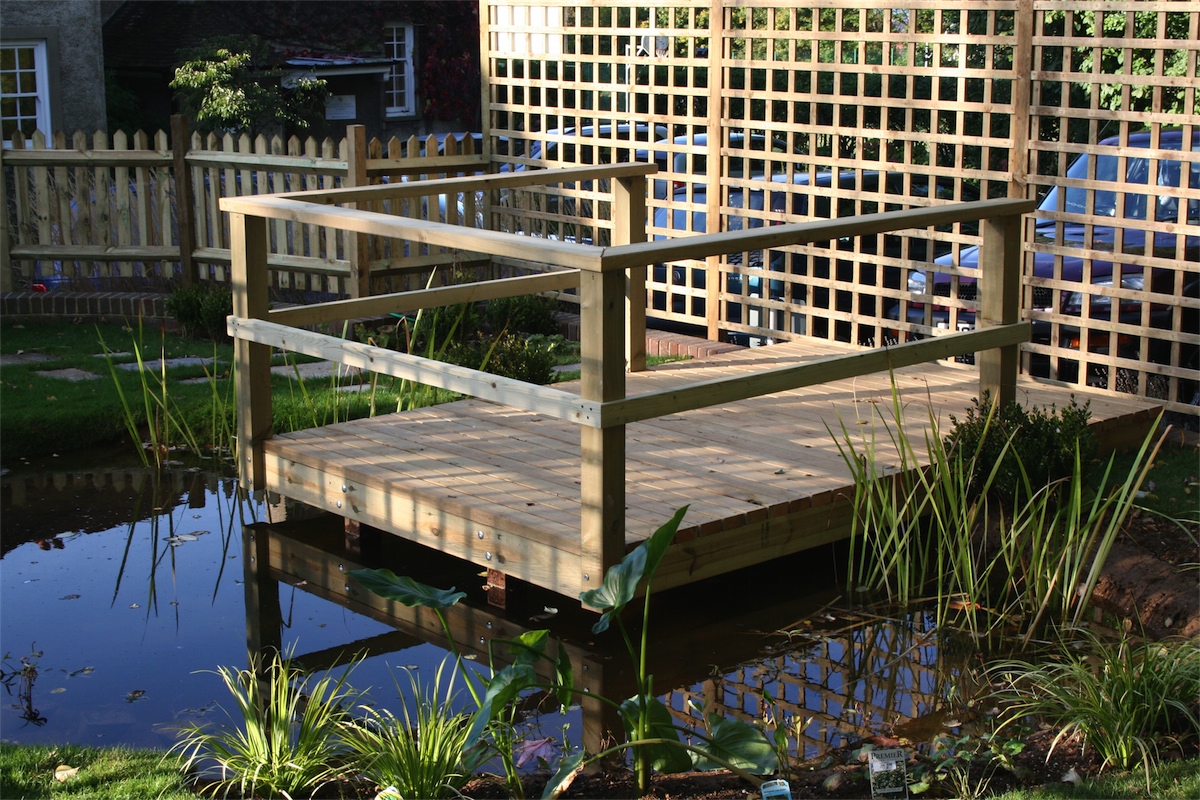 Timber jetty with railing, over a pond created with soil over the pond liner to attract wildlife.
